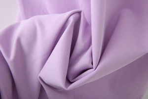 Nahaufnahme von weichem lila Strickstoff mit glatter Textur und elegantem Faltenwurf