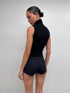 Slim fit black sleeveless turtleneck top paired with tight low-waist mini hot pants