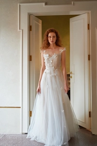 Détail d'une robe de mariée blanche avec des appliques de papillons 3D sur tulle léger