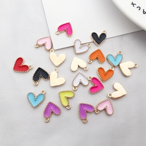 Colorful heart pendants with gold metal frames and enamel inlay displayed on gray fabric