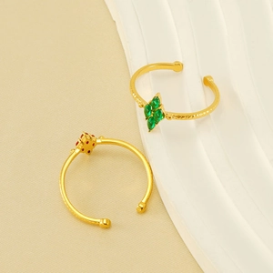 Adjustable gold hammered rings with green and orange zircon gemstones on white wavy props