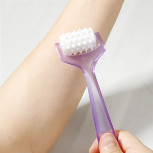 Handheld manual body roller massager with purple handle used for arm muscle relief