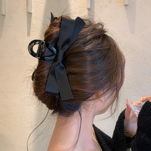Close-up of a black satin bow hair claw clip styled on long brunette hair for women