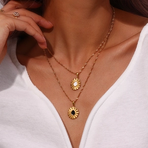 Detail of gold double-layer necklace with sunburst pendant and heart inlay design