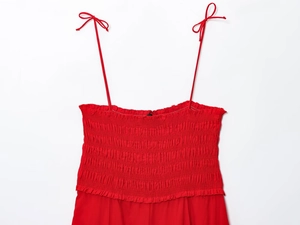 Detail of red cotton midi dress featuring elastic smocked chest and bow-tie straps