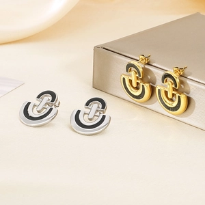 Close-up of gold and silver D-shaped stainless steel earrings with black enamel inlay