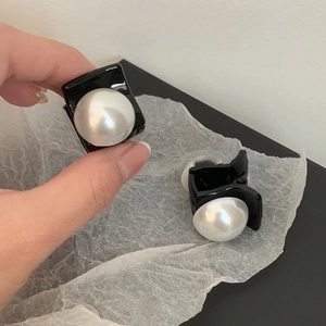 Detail of two mini black hair clips with white pearls on a minimalist background