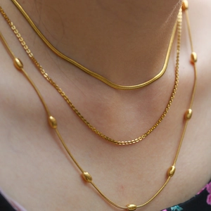 Ensemble de trois colliers dorés avec chaîne serpent et perles sur chaîne plate élégante