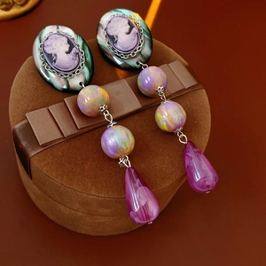 Close-up of vintage resin cameo earrings with green and purple resin beads and silver trim