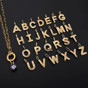 Detailed view of textured gold alphabet charms and a purple gemstone necklace set