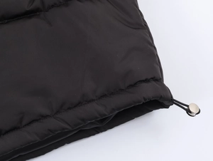 Detailed view of black puffer jacket hem with adjustable drawstring and metal toggle