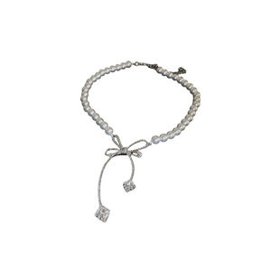 Collier de perles avec pendentif nœud argenté et cristaux suspendus sur blanc