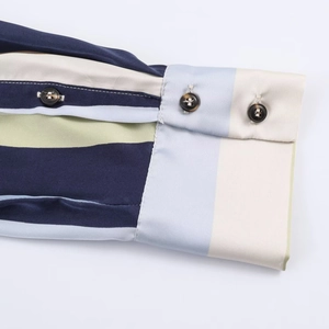 Detailed close-up of striped satin shirt cuff with dark tortoiseshell buttons
