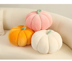 Close-up of three plush pumpkin pillows in corduroy fabric on a soft beige sofa