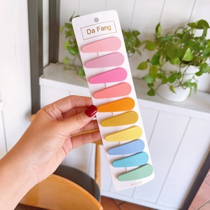 Close-up of ten colorful matte drop-shaped hair clips on a white display card