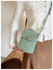 Detail of mint green PU leather mini crossbody bag with metal clasp worn by a model