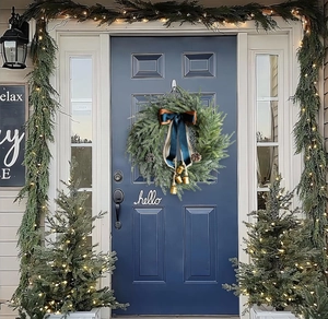 Close-up of Christmas wreath with blue bow and golden bells on a front door