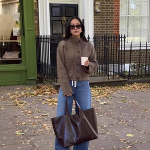 Gilet en maille marron pour femme avec jean bleu et sac cabas en cuir dans la rue