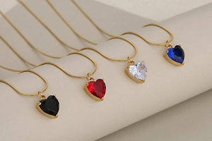 Detail of colorful crystal heart pendants on golden snake chains in four elegant colors