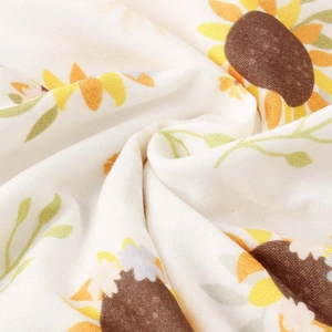 Close-up of soft cotton muslin baby blanket with yellow sunflower prints and fringe