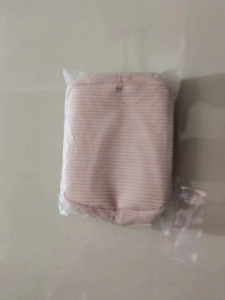 Detail view of pink striped travel cosmetic bag in protective plastic packaging