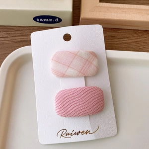 Close-up of pink plaid and wavy fabric hair clips set on a white display card