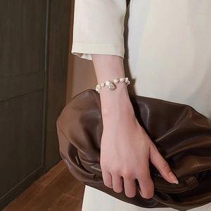 Elegante vergulde parelarmband met schelphanger en natuurlijke witte parels