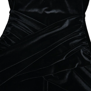 Detailed macro view of black velvet dress featuring crisscross ruching and textured pleats