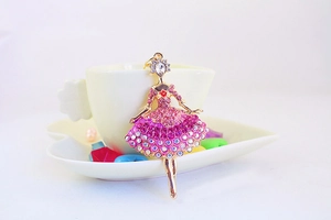 Detailed close-up of a golden ballerina keychain with pink rhinestones on a heart dish