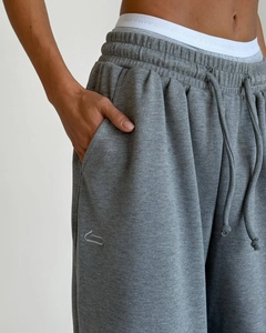 Dettaglio dei pantaloni sportivi grigi vintage con coulisse e ricamo del logo