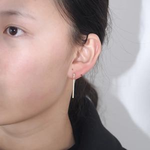Close-up of golden s925 silver rectangle earrings with pavé zircons on model ear