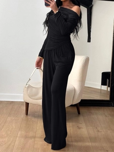 Elegant black long sleeve off-shoulder top and wide leg pants set in a minimalist room