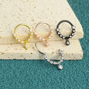 Detail of cubic zirconia nose rings with teardrop pendants in gold silver and black