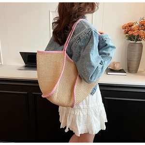 Detailed side view of a large woven straw tote bag with vibrant pink shoulder straps