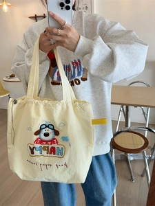 Pale yellow canvas tote bag with puppy embroidery and HAPPY text shown in mirror selfie