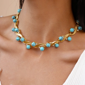 Close-up of golden turquoise necklace with diamond accents on model neck area