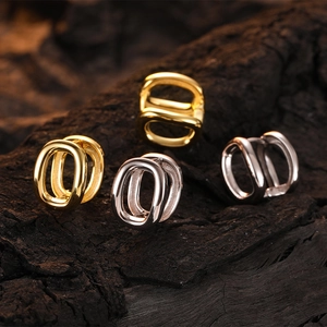 Elegant U-shaped hoop earrings in gold and silver finish on textured dark wood surface