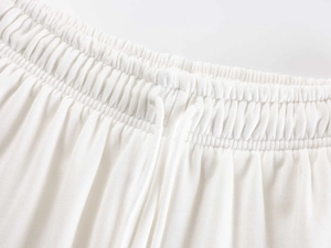 Detail of the elastic waistband and adjustable drawstring on white knitted sports pants
