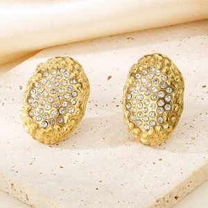 Détail de boucles d'oreilles ovales dorées en acier inoxydable avec pavé de diamants brillants