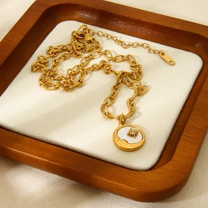 Gold-plated stainless steel chain necklace with shell sun pendant on a soft beige cushion