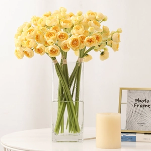 Artificial yellow camellia bouquet in a square glass vase with realistic faux water