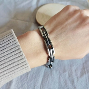 Dettaglio del bracciale geometrico multistrato nero e argento indossato dal modello