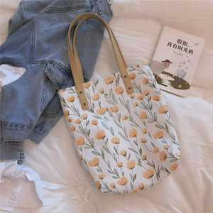 Détail du sac cabas en coton fleuri avec poignées en cuir et rivets métalliques