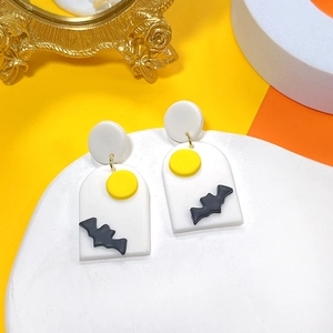Detail of handmade clay Halloween earrings with black bat and yellow moon design