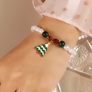 Close-up of beaded Christmas bracelet featuring a green enamel tree charm and pearls