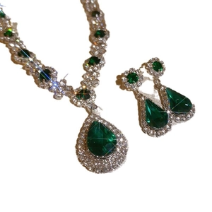 Elegant emerald teardrop necklace and earrings set with micro-pave crystals on white backdrop