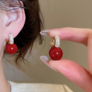 Detail showing elegant gold huggie earrings with red resin beads and pave zircon