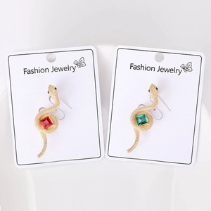 Detailed view of snake-shaped earrings in gold finish with red and green gemstone accents