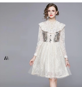 Detail of white lace dress showing ruffled high neck and delicate floral embroidery