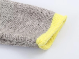 Detail of grey knitted sweater sleeve with vibrant yellow ribbed cuff and texture